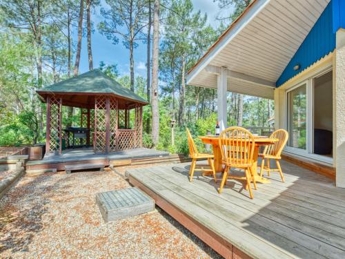 une terrasse en bois avec un kiosque, une table et des chaises dans l'établissement Holiday Home Golf Loisirs-1 by Interhome, à Lacanau-Océan