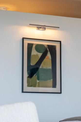 a picture hanging on a white wall with a white couch at Schulphoek Seafront House in Hermanus