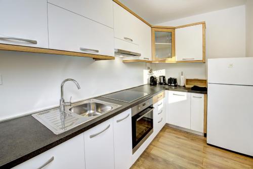 a kitchen with white cabinets and a sink at Cool Šilo Appartement Resort in Šilo