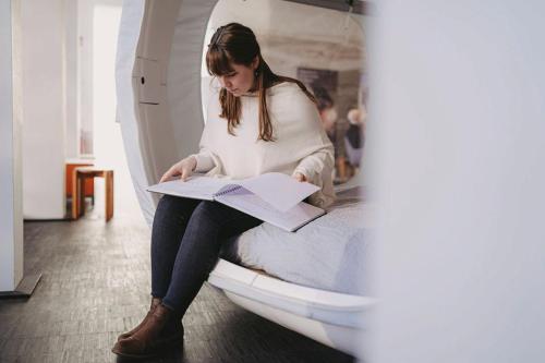 a woman sitting on a bed reading a book at Nachts allein im Museum - Indoor Cube in Lüneburg
