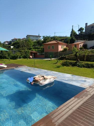 a woman laying on a raft in a swimming pool at Quinta dos Caseiros do Paço de Giela in Arcos de Valdevez