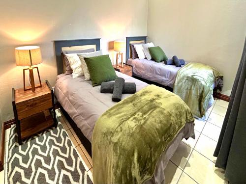 a bedroom with two beds with green pillows at Fish Eagle Manor in Warmbaths