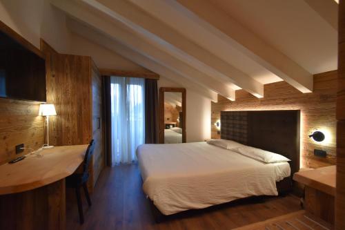 a bedroom with a bed and a desk in a room at Hotel Garni Arnica ***S in Madonna di Campiglio