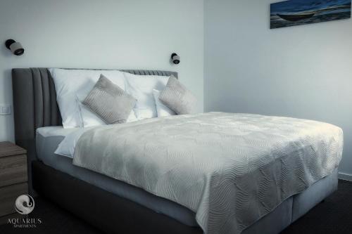 a bedroom with a bed with white sheets and pillows at Aquarius Apartments in Miskolctapolca