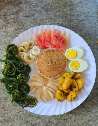 a plate of food with a sandwich and fruits and vegetables at Mundum Farm Stay in Dhulikhel