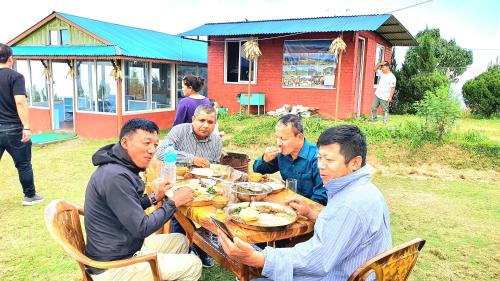 a group of men sitting around a table eating food at Mundum Farm Stay in Dhulikhel