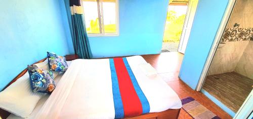 a bedroom with a bed with a blue wall at Mundum Farm Stay in Dhulikhel