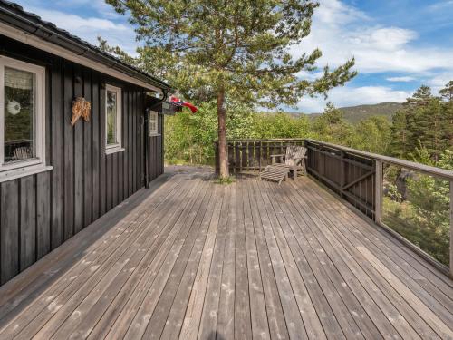 a wooden deck on a house with a tree at Chalet Knøttebu by Interhome in Øyuvstad
