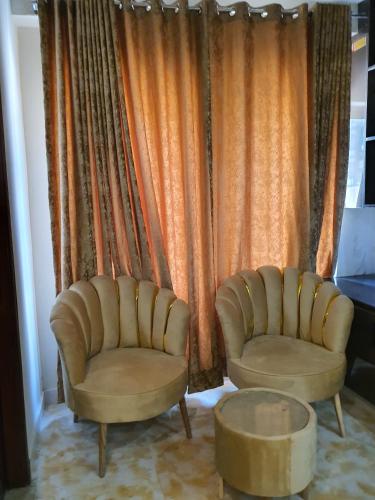 two chairs and a table in front of a curtain at Pova Hotel Suits and Apartments in Rawalpindi