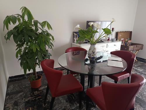 a dining room with a glass table and red chairs at A Casa di Luca in Faenza