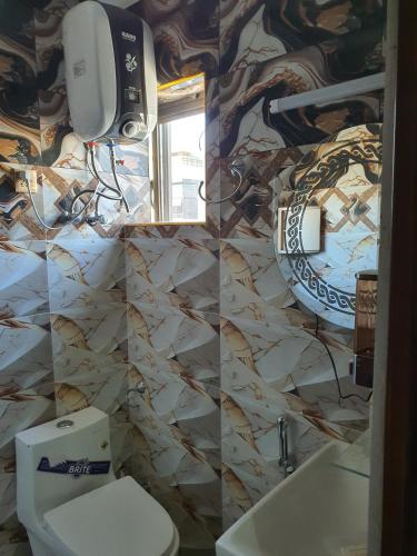 a bathroom with a toilet and a sink and a mirror at Pova Hotel Suits and Apartments in Rawalpindi