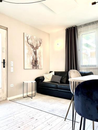 a living room with a black couch and a picture of a deer at Tiny Ferienhaus 4 am Rimbach in Steinau an der Strasse in Steinau an der Straße