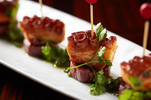 a plate of food with meat and vegetables on skewers at Four Seasons Hotel New York in New York