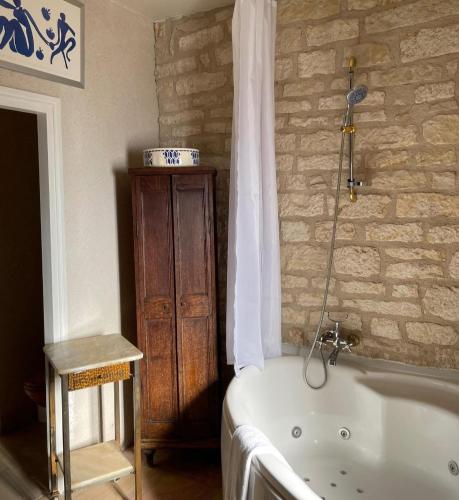 une baignoire dans une pièce avec un mur en pierre dans l'établissement La Maison d'Alienor - Les Clos - 2ème Etage - Chablis 89, à Chablis