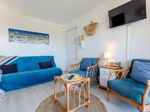 un salon avec un canapé bleu et des chaises dans l'établissement Apartment Le Clos Mathilde-19 by Interhome, à Cabourg