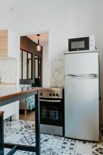 Il comprend une cuisine équipée d'un réfrigérateur blanc et d'une cuisinière. dans l'établissement l'Amiral, au Havre