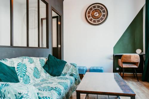 un salon avec un canapé et une horloge au mur dans l'établissement l'Amiral, au Havre