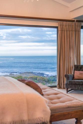 a bedroom with a large window overlooking the ocean at Schulphoek Seafront House in Hermanus