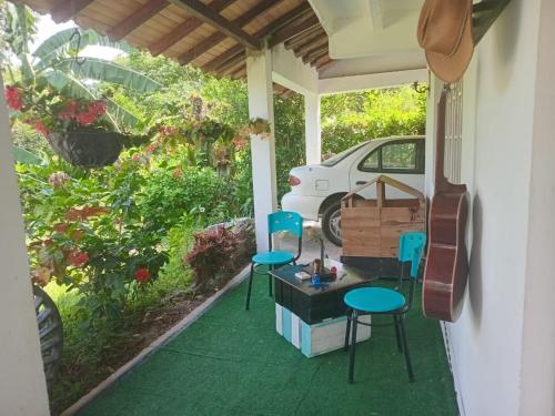 a porch with two chairs and a table and a car at Trekkers haven Enjoy Colombia Ecoliving in Piedecuesta