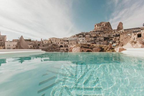 a view of a pool with a city in the background at Millstone Cave Suites Hotel in Uchisar
