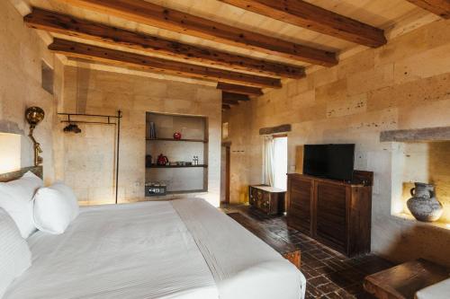 a bedroom with a bed and a television in it at Millstone Cave Suites Hotel in Uchisar