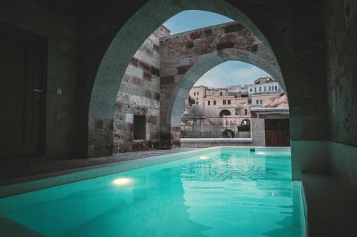 a large swimming pool in a building with an arch at Millstone Cave Suites Hotel in Uchisar