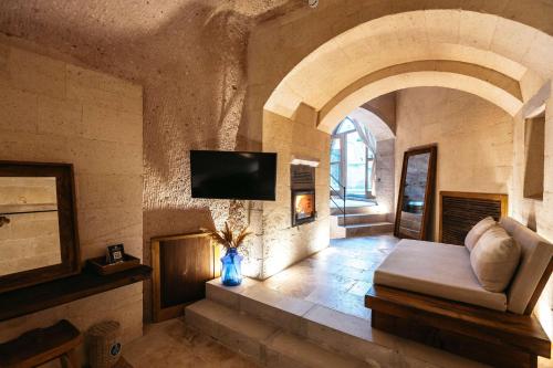 a living room with a fireplace and a tv on a wall at Millstone Cave Suites Hotel in Uchisar