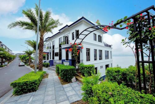 a white house with a palm tree and a street at Happy Home in Ha Long