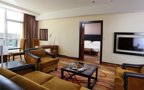 a living room with a couch and a television at Millennium Airport Hotel Dubai in Dubai