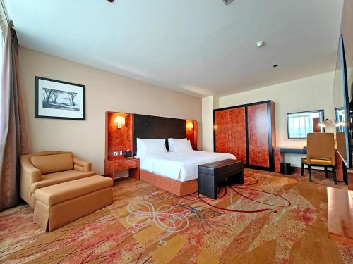 a hotel room with a bed and a chair at Millennium Airport Hotel Dubai in Dubai