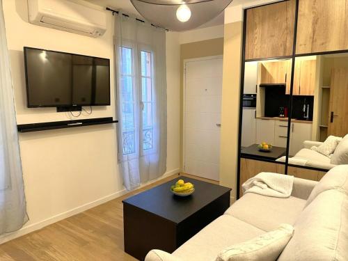 un salon avec un canapé et une télévision sur un mur dans l'établissement Studio Californien à deux pas de la plage, à Nice