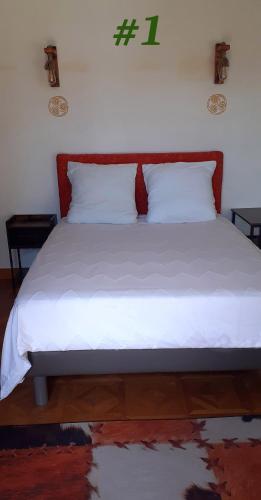 - un lit avec des draps blancs et une tête de lit rouge dans l'établissement La Couleur du Temps, à Couiza
