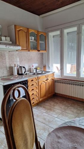 a kitchen with wooden cabinets and a table in it at Apartman Maja in Srbobran