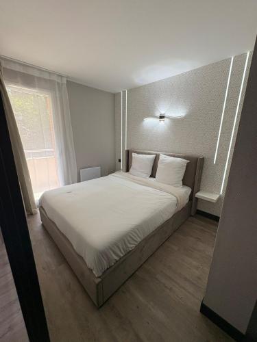 une chambre avec un lit avec des draps blancs et une fenêtre dans l'établissement Apartment in a hotel residence, à Toulouse
