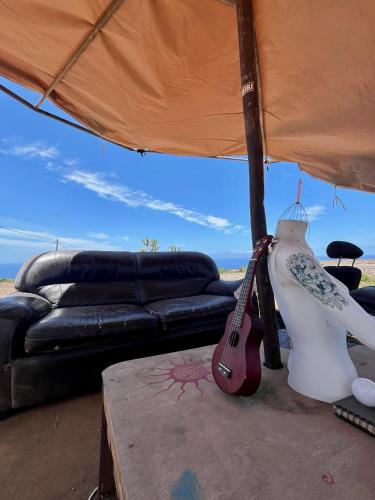 a living room with a guitar and a couch at Adeje - TwinFin Hostel & Surf Yoga Camp in Callao Salvaje