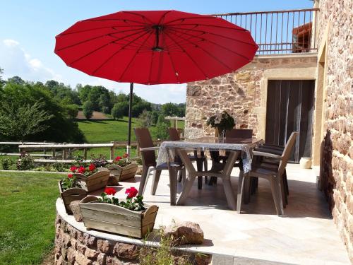 - une table et des chaises avec un parasol rouge sur la terrasse dans l'établissement Le gîte de Montailloux, à Saint-Laurent-en-Brionnais