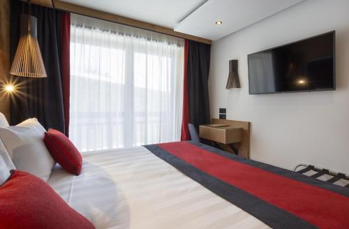 a bedroom with a large bed with a television on the wall at Hôtel Alparena & Spa - 4 étoiles in La Rosière