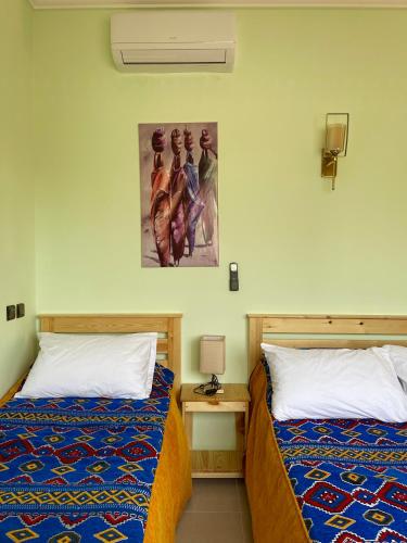 a bedroom with two beds and a picture on the wall at Dyafat Abla in Oulad Akkou
