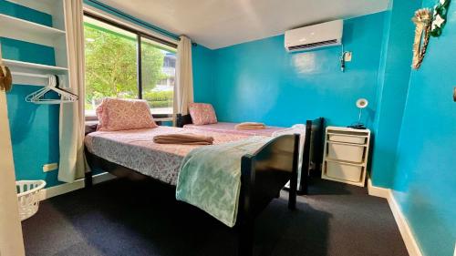a room with two beds in a room with blue walls at Ngermid Oasis - 2 BD & 1 BA Cozy Cottage in Koror