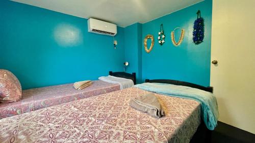 a bedroom with two beds with blue walls at Ngermid Oasis - 2 BD & 1 BA Cozy Cottage in Koror