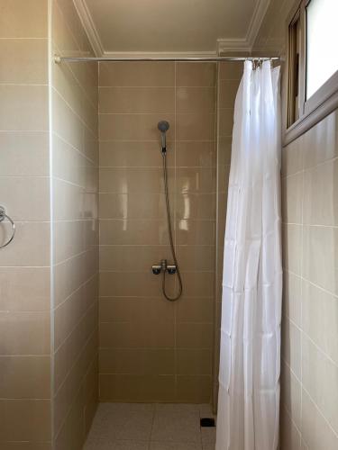 a shower with a white shower curtain in a bathroom at Dyafat Abla in Oulad Akkou