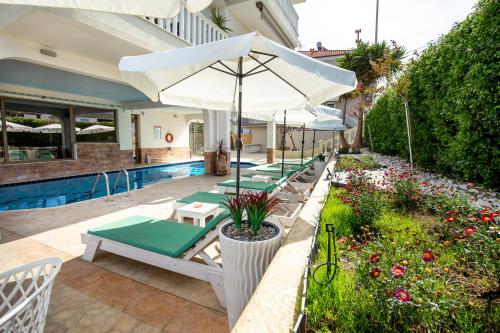 a row of lounge chairs and an umbrella next to a pool at Garden in Limenaria