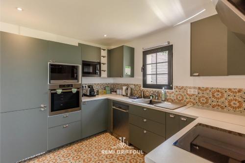 une grande cuisine avec des placards verts et un évier dans l'établissement Villa Biloba - sea view and beach access 10 People, à Cricquebœuf