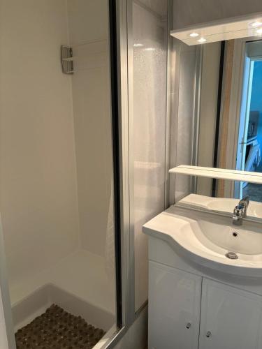 une salle de bain blanche avec un lavabo et une douche dans l'établissement Maison climatisee proche plage avec piscine, à Saint Cyprien Plage