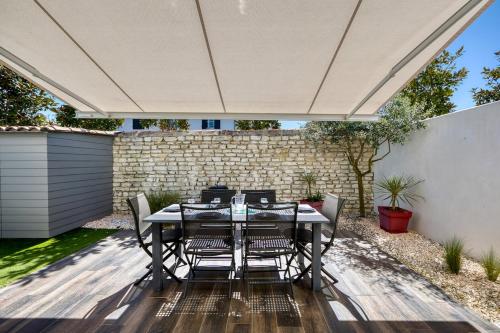 une terrasse avec une table et des chaises sous un parasol dans l'établissement 219 Thoiras 6 House, garden and parking, à Saint-Martin-de-Ré