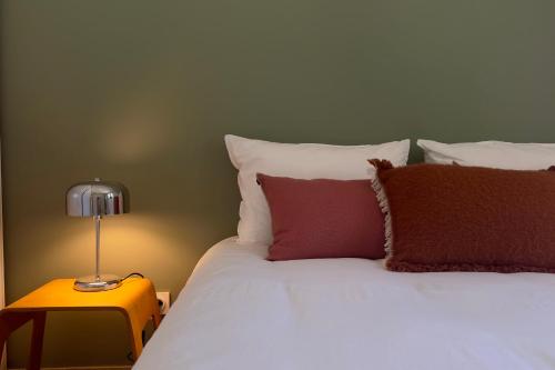 un lit avec des draps blancs et des oreillers rouges et une lampe dans l'établissement La villa des Gypières, à LʼIsle-sur-la-Sorgue