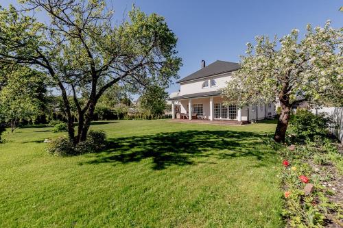 a white house with trees in the yard at Luxury Villa in Pärnu, walking distance from the beach and city centre in Pärnu