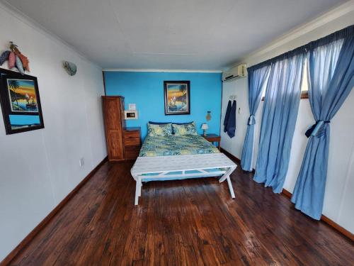 a bedroom with a bed with blue walls and wooden floors at Xai Xai Mozambique, Fish Eagle, Xai Xai Beach Front in Xai-Xai