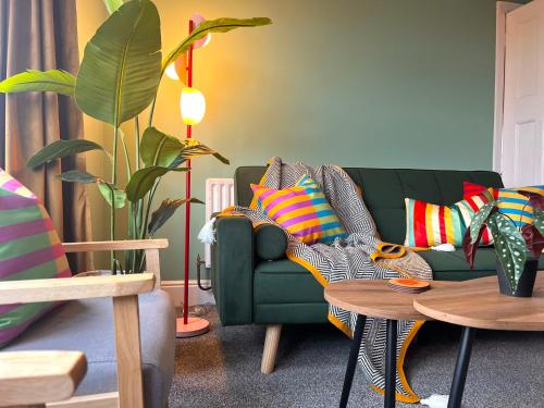 a living room with a green couch with colorful pillows at The Vinyl, 1 bed flat near Southampton Uni in Southampton