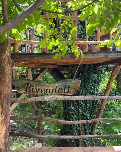 a wooden sign that reads riveryardilli hanging from a tree at Rivendell Treehouse in Chiozza